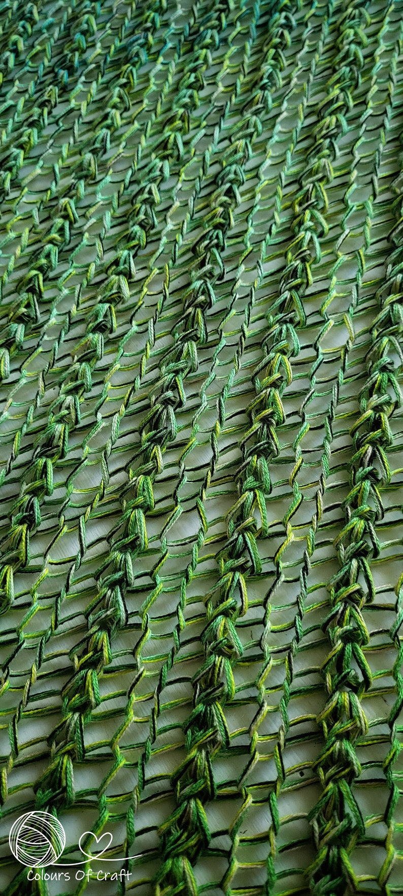 Op de afbeelding: Een groene en gele gehaakte stof met een geweven patroon. De stof is gemaakt van dik garen en heeft een losse, open weving.
