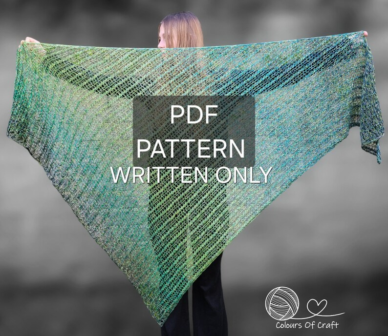 Op de afbeelding: Een vrouw draagt een groen en blauwe gehaakte sjaal met de tekst "PDF PATTERN WRITTEN ONLY" op een wit rechthoek. De tekst "Colours Of Craft" staat onder een bol garen met een hart.