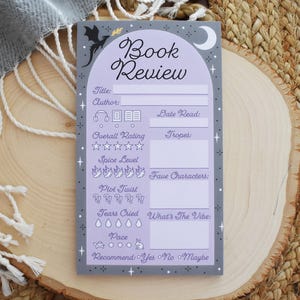 May include: A lavender and gray book review notepad with the words "Book Review" at the top. The notepad includes sections for title, author, rating, tropes, and more. A dragon and moon are at the top.