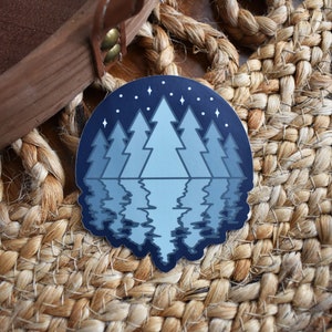May include: A blue and white sticker with a silhouette of a forest reflected in a lake under a starry night sky.