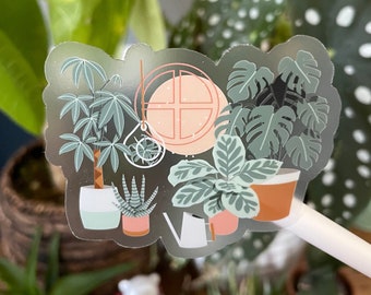 May include: A clear sticker with a whimsical illustration of potted plants, including a monstera, a succulent, and a fiddle leaf fig. The sticker features a pink and white window with a cross design and a small watering can.
