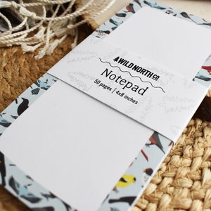 Puede incluir: Un bloc de notas con un patr&oacute;n de p&aacute;jaros azul y blanco en la portada. El bloc de notas tiene 50 p&aacute;ginas y mide 10,2x20,3 cm. El texto en la portada dice "Wild North Co. Notepad 50 pages | 4x8 inches".