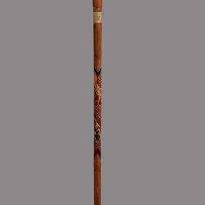 May include: A wooden walking stick with a carved cardinal head at the top. The stick is decorated with intricate carvings of flowers and leaves.
