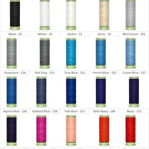 May include: A collection of 15 spools of Gutermann thread in various colors, including black, white, gray, blue, navy, red, pink, and peach. Each spool is labeled with the color name and number.