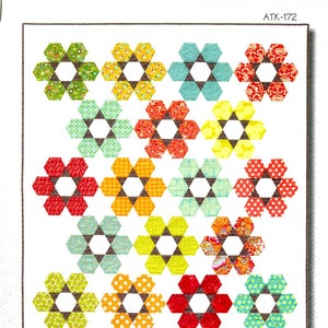 Può includere: Un modello di quilt intitolato "Hexie Garden" con un motivo floreale ripetuto. I fiori sono composti da forme esagonali colorate in vari modelli e colori, tra cui verde, giallo, arancione, rosso e blu. Il logo Atkinson Designs è in alto.