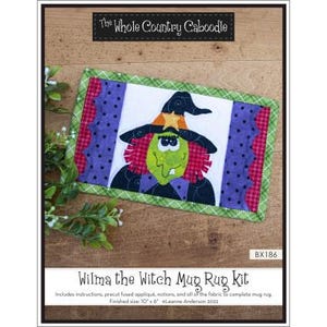 May include: A rectangular Wilma the Witch mug rug kit. The rug features a green-faced witch with a black hat and orange star. The rug has a white center, purple polka dot sides, and a green border. The text "The Whole Country Caboodle" is at the top.