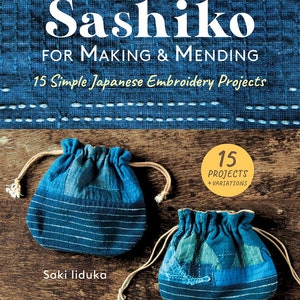 以下が含まれることがあります： Saki liduka 著「Sashiko: For Making & Mending 15 Simple Japanese Embroidery Projects」というタイトルの本。表紙には、木製の表面に青い布製の巾着が2つ置かれている。この本は Tuttle によって出版されている。