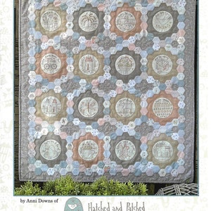 May include: A quilt pattern called "Around Town" by Anni Downs of Hatched and Patched. The quilt features a patchwork design with 16 circular motifs, each depicting a different scene from a town. The motifs are surrounded by a hexagonal pattern in shades of gray, blue, and pink.