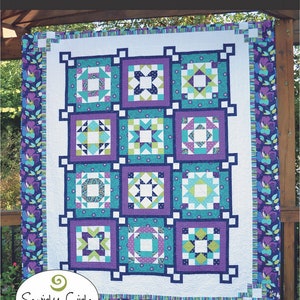 May include: A colorful quilt with a white background and a repeating pattern of squares in teal, purple, and green. The quilt features the text "Daydream" and "Swirly Girls". The border has a floral design.
