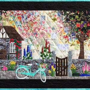 May include: A colorful quilt depicting a quaint cottage with a stone wall, a bicycle with a basket of flowers, and a tree with red flowers. The background is a patchwork of floral fabric.