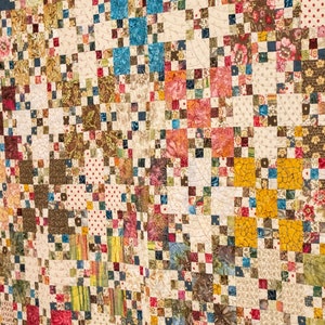 May include: A patchwork quilt with a variety of colorful squares and patterns. The quilt is made with a variety of fabrics, including floral prints, geometric patterns, and solid colors. The quilt is a beautiful example of traditional quilting.