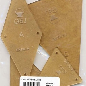 May include: A set of three clear plastic stencils for quilting, labelled "Alaska Stencil" and "LBQ-0725-T". The stencils are shaped like diamonds and have a basket design.