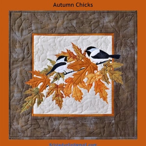 Könnte beinhalten: Ein Quiltblock mit zwei schwarzen Kapuzenmeisen, die auf einem Zweig mit Herbstblättern sitzen. Der Hintergrund ist ein cremefarbener Stoff mit einem gesteppten Muster. Der Quiltblock ist mit einem braunen Stoffrand umrahmt. Der Text "Trouble & Boo Designs" und "Autumn Chicks" ist über dem Quiltblock gedruckt. Der Text "Kristadvellie@gmail.com" und "Alle Rechte vorbehalten" ist unter dem Quiltblock gedruckt.