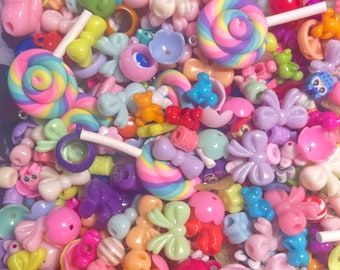 May include: A large assortment of colorful plastic beads, including bows, lollipops, and other shapes. The beads are perfect for making jewelry or other crafts.