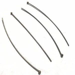 May include: Four silver head pins with gold-colored ball heads.