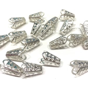 May include: A group of silver metal bead caps with a decorative filigree design. The caps are small and delicate, and they are perfect for adding a touch of elegance to jewelry projects.