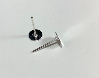 May include: Two silver earring posts with flat round backs. The posts are about 1 inch long.