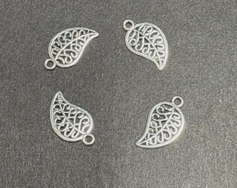 Op de afbeelding: Vier zilverkleurige metalen bedels in de vorm van bladeren. Elke bedel is voorzien van een ingewikkeld, opengewerkt filigraanpatroon over het hele bladlichaam en bevat een kleine ronde lus aan de bovenkant voor bevestiging, met een metalen afwerking.