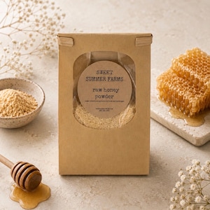 May include: A brown paper package with a clear window displays raw honey powder. A bowl of powder, a wooden honey dipper, and a piece of honeycomb are also visible. The package has a circular label that reads "Sweet Summer Farms raw honey powder".