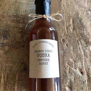 Peut inclure: Une bouteille en verre de vodka au pain perdu infusée au miel, avec une étiquette brune qui indique "Sweet Summer Farms French Toast Vodka Infused Honey".