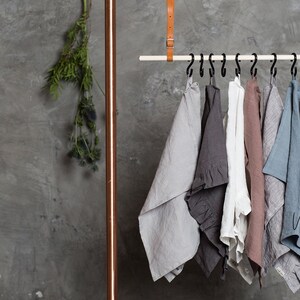 May include: Six linen tea towels hanging on a rack. The towels are in various shades of gray, brown, and blue. The text "Wonder Linen" is visible in the bottom right corner of the image.