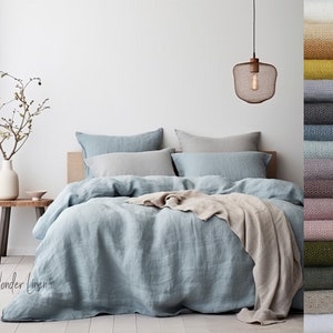 May include: A light blue linen duvet cover with a beige throw blanket on a bed with white and gray linen pillowcases. The text "Wonder Linen" is visible in the bottom left corner of the image. A variety of linen fabric swatches in different colors are shown on the right side of the image.