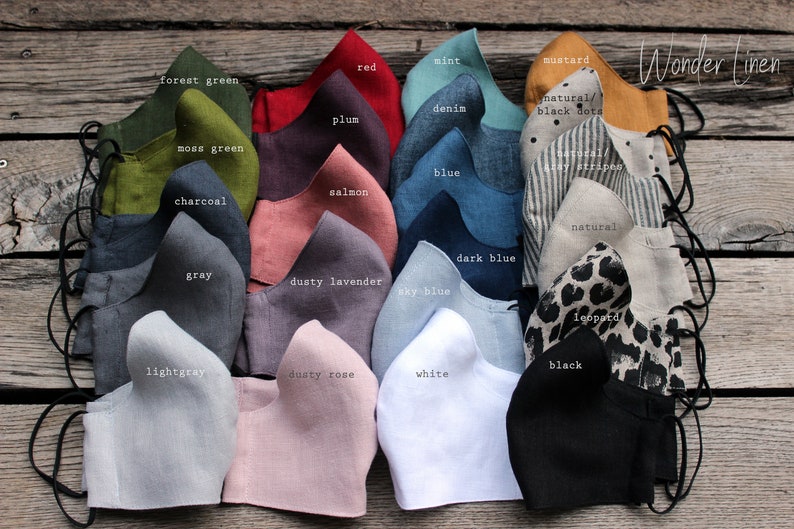 May include: A collection of 20 linen face masks in various colors and patterns, including forest green, moss green, charcoal, gray, light gray, dusty lavender, sky blue, dark blue, white, dusty rose, red, plum, salmon, mint, denim, blue, mustard, natural with black dots, natural with gray stripes, natural, and leopard. The masks are arranged in two rows of ten, with the colors and patterns alternating. The text "Wonder Linen" is visible in the top right corner of the image.