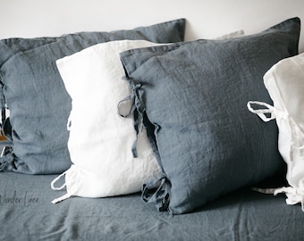May include: Four pillowcases in a mix of white and blue linen. The pillowcases have ties at the corners. The pillowcases are arranged on a blue linen bedspread. The text "Wonder Linen" is visible in the bottom left corner of the image.