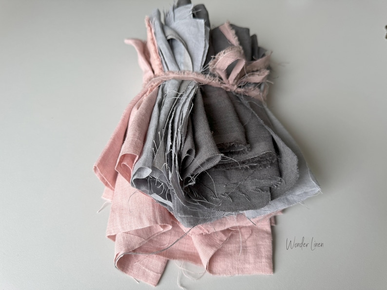 May include: A bundle of pink and gray linen fabric scraps tied together with a string. The fabric is soft and textured, and the colors are muted and calming. "Wonder Linen" is written in white text on the bottom right corner of the image.