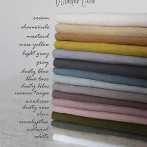  May include: A stack of linen fabric samples in various colors, including cream, mustard, and dusty rose. The text "Wonder Linen" is written in cursive at the top. The image displays a range of neutral and muted tones, suitable for home decor or apparel.