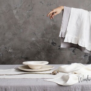 May include: White linen table runner and napkins with a white ceramic bowl and plate on a gray table. The text "Wonder Linen" is visible in the bottom right corner of the image.