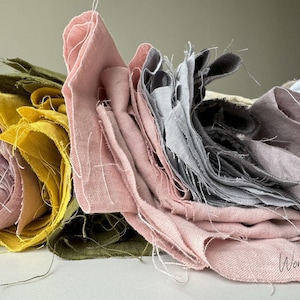 May include: A stack of fabric scraps in various shades of pink, gray, yellow, and green. The fabric is linen and has a natural, slightly textured look. The fabric scraps are arranged in a pile, with the pink fabric on top. The text "Wonder Linen" is visible in the bottom right corner of the image.