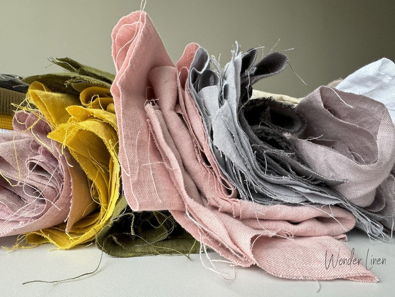 May include: A stack of fabric scraps in various shades of pink, gray, yellow, and green. The fabric is linen and has a natural, slightly textured look. The fabric scraps are arranged in a pile, with the pink fabric on top. The text "Wonder Linen" is visible in the bottom right corner of the image.