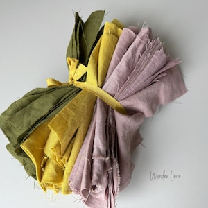 May include: A bundle of fabric scraps in shades of green, yellow, and pink, tied together with a yellow ribbon. The fabric is linen and has a natural, rustic look. The text "Wonder Linen" is visible in the lower right corner of the image.