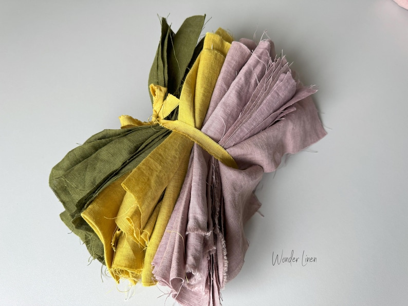 May include: A bundle of fabric scraps in shades of green, yellow, and pink, tied together with a yellow ribbon. The fabric is linen and has a natural, rustic look. The text "Wonder Linen" is visible in the lower right corner of the image.