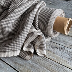 May include: A roll of brown and white gingham linen fabric. The fabric is folded and rolled up on a wooden surface. The text "Wonder Linen" is visible in the lower right corner of the image.