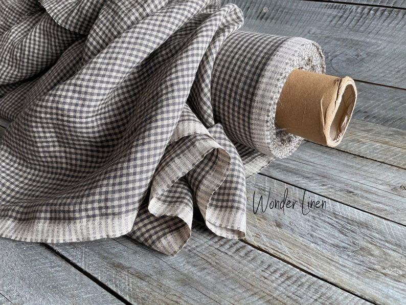 May include: A roll of brown and white gingham linen fabric. The fabric is folded and rolled up on a wooden surface. The text "Wonder Linen" is visible in the lower right corner of the image.