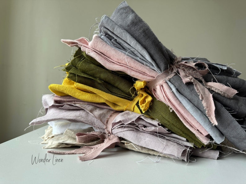May include: A stack of folded linen fabric in various shades of gray, pink, yellow, and green. The fabric is tied together with a string and has frayed edges. The text "Wonder Linen" is visible at the bottom of the image.