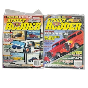 May include: Two vintage "Street Rodder" magazines in plastic sleeves. The covers feature classic cars in various colors, with bold yellow and red text. One magazine highlights "Street Rod of the Year!" and the other, "Grand National Roadster Show."