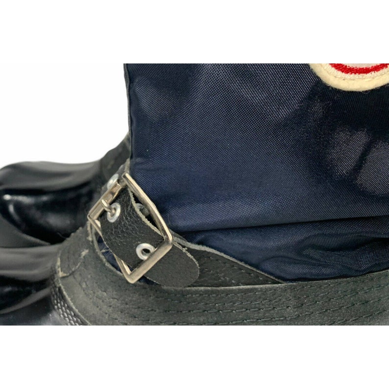 K&ouml;nnte beinhalten: Schwarze Lederstiefel mit blauem Nylon-Obermaterial und einer silbernen Schnalle. Die Stiefel haben einen umklappbaren Schaft.