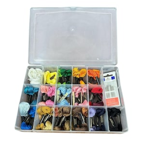 May include: A clear plastic organizer box filled with colorful embroidery floss in various shades of blue, pink, yellow, green, orange, and red. The box also contains a packet of needles.