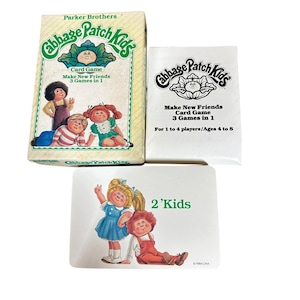 May include: A Cabbage Patch Kids card game set including a rectangular box, a white instruction booklet, and a single playing card. The box and booklet feature the text Cabbage Patch Kids Make New Friends 3 Games in 1. The card shows two children and the text 2 'Kids.
