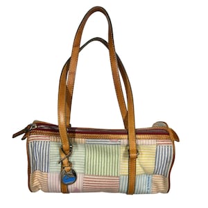 May include: A cylindrical handbag featuring a patchwork design of pastel-colored striped fabric squares in blue, green, yellow, and pink. It includes tan leather handles, a top zipper closure, and a silver-toned metal duck charm hanging from one strap.