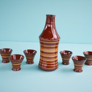 Op de afbeelding: Een set van bruin en tan gestreepte keramische sake bekers en een bijpassende sake fles.