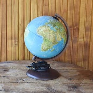 May include: A blue globe with a brown stand on a wooden table. The globe shows the continents and oceans of the world.