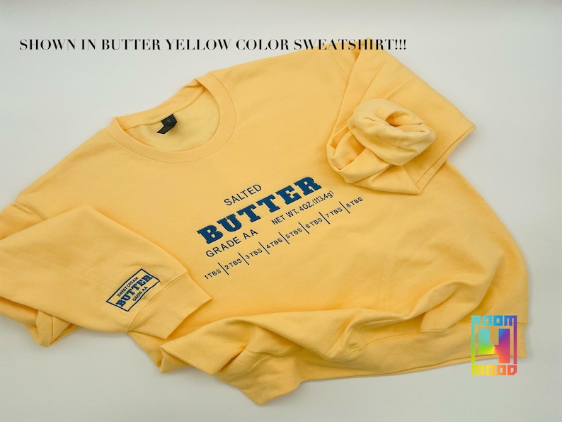 May include: A yellow sweatshirt with the text "SALTED BUTTER GRADE AA NET WT. 402. (113.4g) 178g | 278g | 378g | 478g | 578g | 778g | 878g" printed on the front.