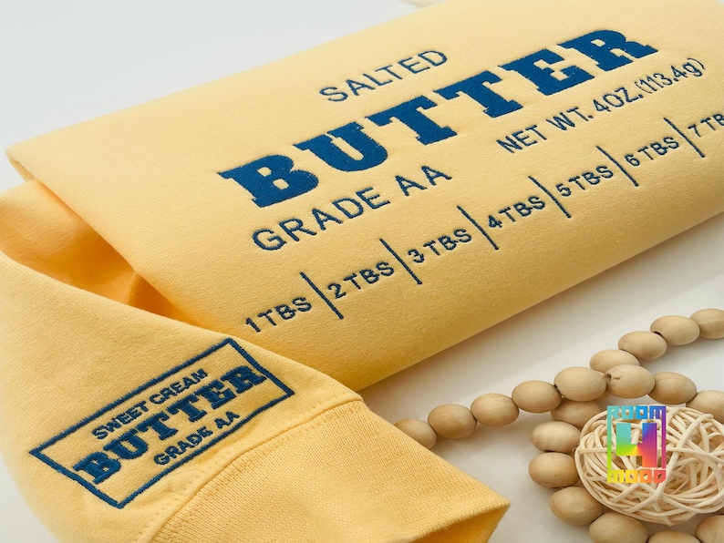 May include: Yellow sweatshirt with the text "SALTED BUTTER GRADE AA" and "NET WT. 4OZ. (113.4g)" printed on the front. The text "SWEET CREAM BUTTER GRADE AA" is printed on the sleeve.