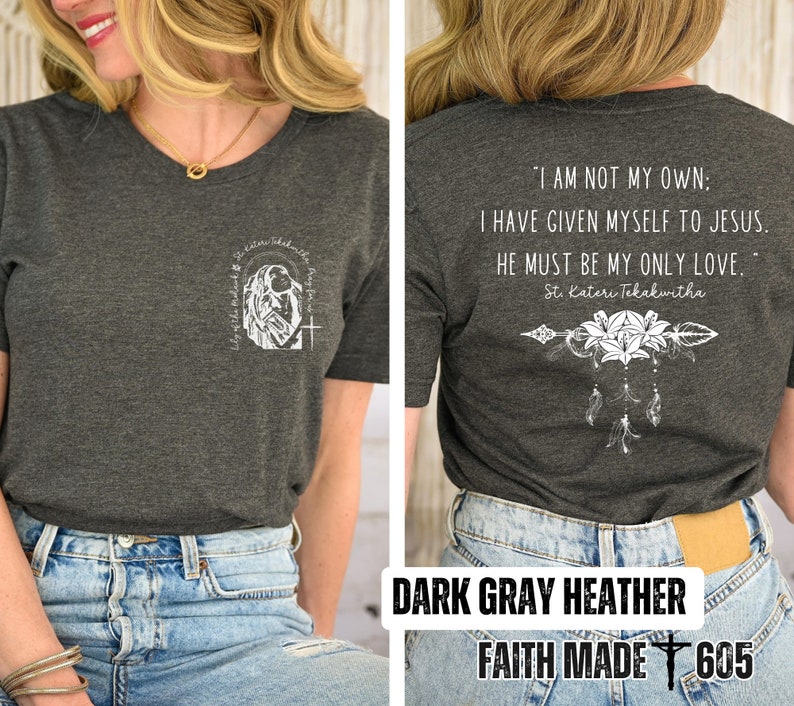 May include: Dark gray heather t-shirt with a white graphic of a woman praying with the text "Pray for" and a cross. The back of the shirt has a white graphic of flowers and an arrow with the text "I am not my own: I have given myself to Jesus. He must be my only love. St. Kateri Tekakwitha". The shirt is labeled "Dark Gray Heather" and "Faith Made 605".