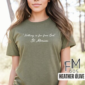 Puede incluir: Una camiseta verde con la cita "Nada est&aacute; lejos de Dios" - Santa M&oacute;nica impresa en blanco en la parte delantera. La camiseta est&aacute; hecha de una tela suave y c&oacute;moda, perfecta para el uso diario.