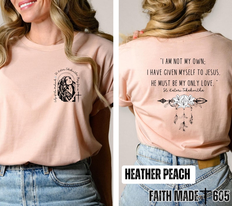 May include: A heather peach colored t-shirt with a graphic of a woman praying on the front and a quote from St. Kateri Tekakwitha on the back. The quote reads "I am not my own: I have given myself to Jesus. He must be my only love." The back of the shirt also features a graphic of an arrow with lilies and feathers. The shirt is labeled "Faith Made 605".